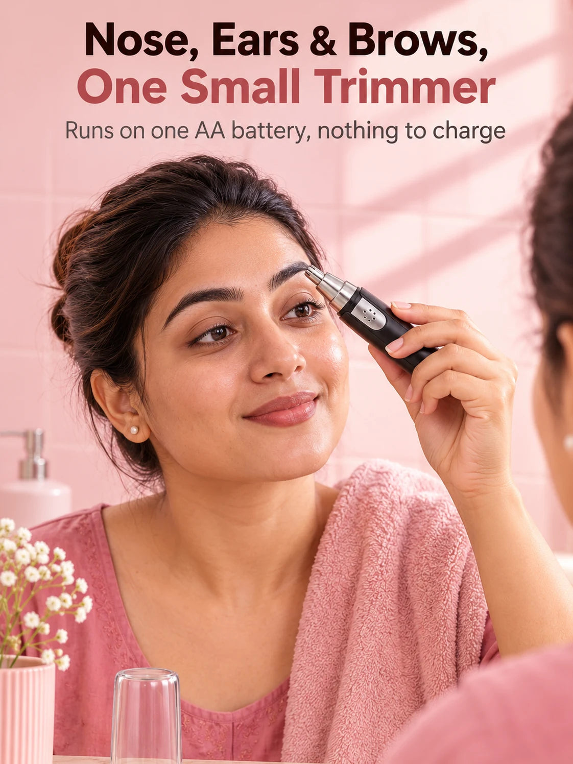 A woman tidying her eyebrow with the black 3-in-1 trimmer at the mirror, its clear cap on the counter